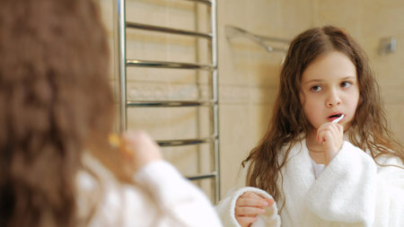 child body care dental health and hygiene. little girl brushing her teeth in front of the mirrorの写真素材
