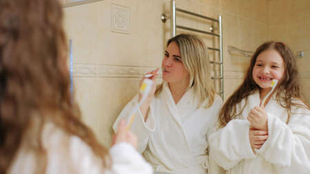 body health care and dental hygiene. family ritual togetherness. mom and daughter brushing teeth in the morningの写真素材