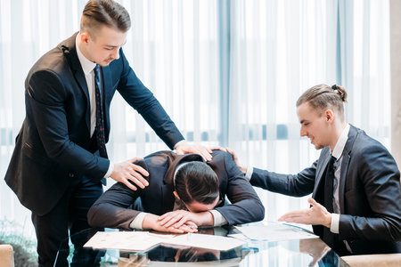 Friendship support help sympathy compassion concept. business partners or colleagues consoling and comforting their distressed and devastated coworkerの写真素材
