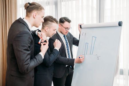 business briefing and goals visualization. company managers writing on the flip chart in office...