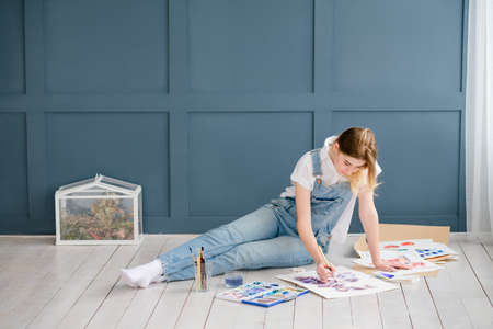 talented artist drawing leisure. creative people lifestyle. relaxed girl painting a picture lying on the floorの写真素材