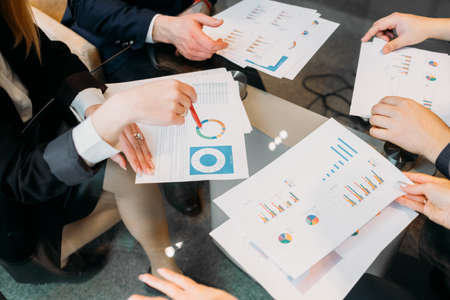 business team communication. results review. data analysis. men and women looking at documents discussing work momentsの写真素材