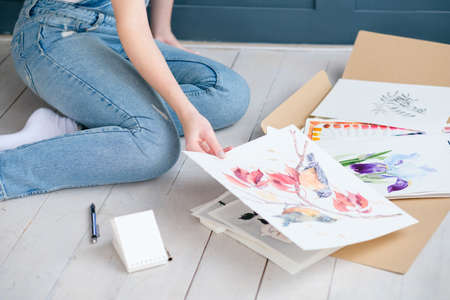 creative leisure. painting hobby. artful personality. painter looking through her drawingsの写真素材