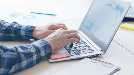 business analysis. office worker typing on laptop and studying papers with graphsの写真素材