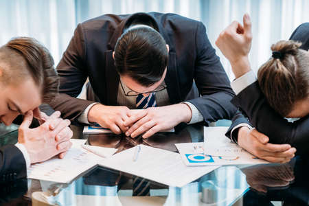 business problems. team of stressed defeated managers sitting in a board room with report documents on the deskの写真素材