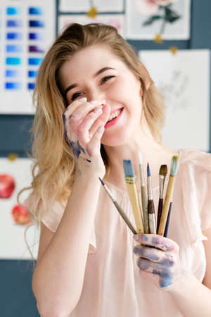 creative art lifestyle. drawing hobby and self expression. painter holding brushes. smiling young beautiful girlの写真素材