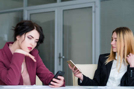 bored indifferent business women on board meeting. waiting for boss. idlers at work killing timeの写真素材