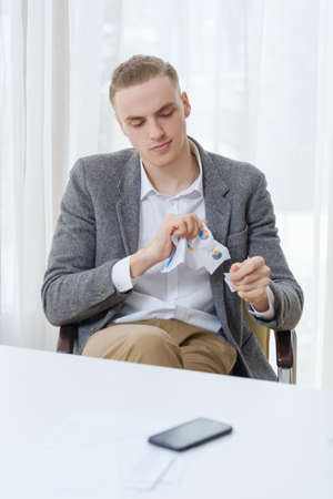 stress relief. calm business man tearing some documents sitting in office.の写真素材