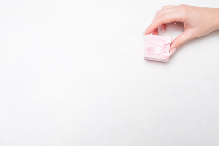 small compliment feminine present on anniversary birthday or valentines day. woman hand holding tiny...