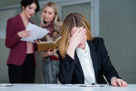 office rush and buzz. woman with a headache in busy and noisy workspace cant concentrate on work