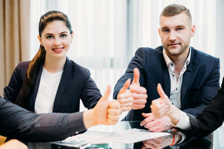 business men and women giving thumbs up. financial success concept. professional executives at workの写真素材