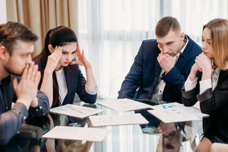 business problems. team of professionals thinking over possible solutions. focused thoughtful stressed managers sitting in a board roomの写真素材