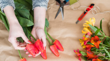 floral workshop. woman hands making a flower arrangement of red tulips. spring bouquetの写真素材