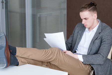young relaxed business man reading documents in office. confident successful manager focused on papers.の写真素材