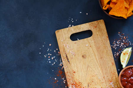 wooden cutting board and salsa sauce in a dipping dish. kitchen utensils and food cooking. free space concept.の写真素材