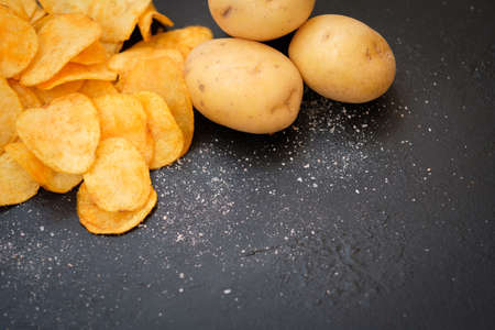 chips preparing. crunchy food crisps cooking. salty ridged fried slices and fresh organic potatoes on dark background. copy space conceptの写真素材