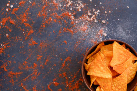 tortilla nacho chips in a bowl. food spices mix background. salty spicy crunchy slices. powdered pepper and salt condimentsの写真素材