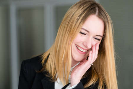 emotion face. happy smiling cheerful pleased woman. business lady at office workspace. young beautiful blond girl portraitの写真素材