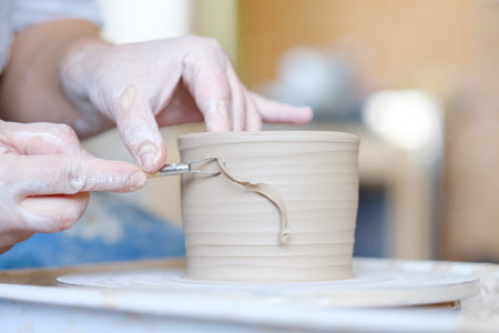 pottery handicraft skills. traditional art of creating ceramics. potter modeling clay jug on turning...