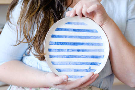 pottery handcraft hobby. woman showing a handmade clay plateの写真素材