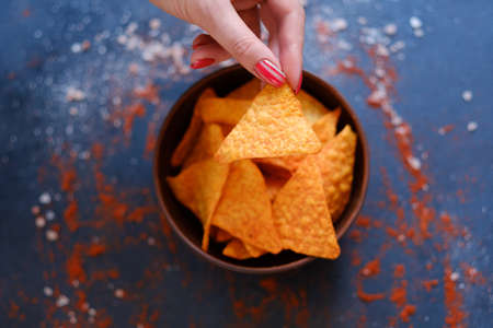 tortilla nacho chips recipe. natural fried crisps in a bowl. woman hand holding crunchy spicy triangular sliceの写真素材