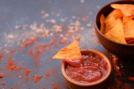 junk fast food and unhealthy eating. nacho tortilla chips in a bowl. triangular crunchy slice dipped in salsa tomato sauceの写真素材