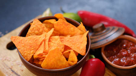 tortilla nacho chips in a bowl. delicious beer chaser. best food for quick snack. crunchy spicy triangular crisps in a bowl on dark backgroundの写真素材
