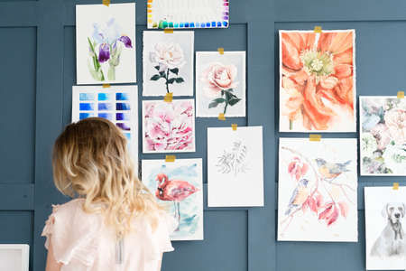 creative art lifestyle. drawing hobby and self expression. painter standing against the wall with her artwork. watercolor drawing assortmentの写真素材