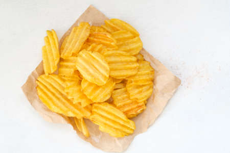 crispy crunchy potato chips are a great party munchies. delicious food snack. waved rudged fried slices on white backgroundの写真素材