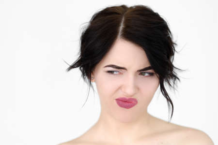 emotion face. discontent dissatisfied envious woman looking sideways and thinking. young beautiful brunette girl portrait on white background.の写真素材