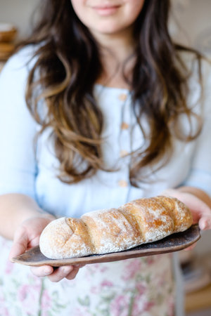 craft bread making. natural organic food produce. woman holding a freshly baked loaf on a tray