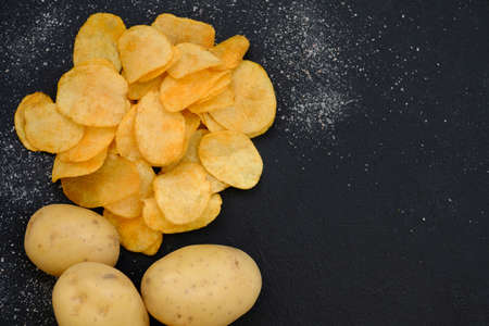 homemade natural fried chips. spicy crisps snack and fresh organic potatoes dark background. free space conceptの写真素材