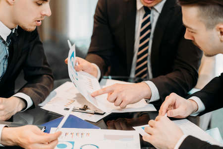 business documents review. man pointing at some important data with a finger. statistics papers analysis. investment rates discussionの写真素材