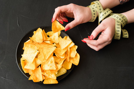 unhealthy fast food snacks. bad nutrition habits. woman breaking her diet eating chips