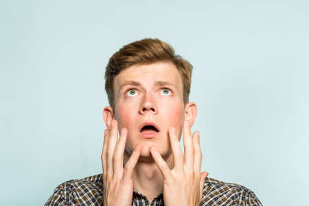 amazed astonished shocked dazed impressed stunned man looking up. portrait of a young guy on light background. emotion facial expression. feelings and people reaction.の写真素材