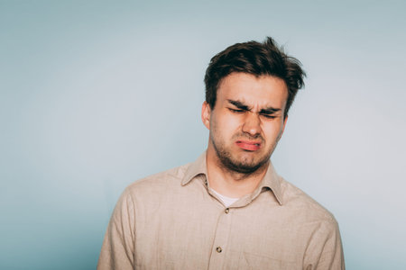 nausea aversion repulsion. reluctant man grimacing in disgust. portrait of a young brunet guy on...