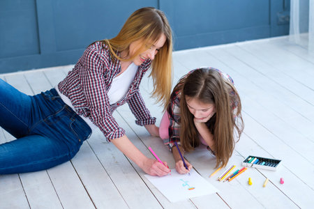 loving family relationship. mothers involvement in kids hobby. mom and daughter drawing together at home.の写真素材