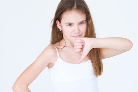 emotion face. disapproving annoyed child showing thumb down. little girl portrait on white...