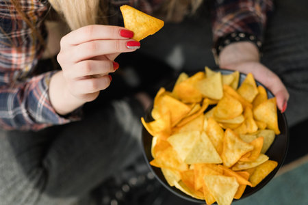 junk fast food and unhealthy nutrition. woman eating chips from a bowl of crunchy crisps