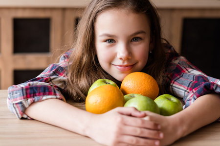 balanced child nutrition. organic fruit for health wellness and fitness of youngsters. girl holding a mix of oranges and apples in handsの写真素材