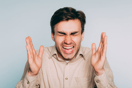 overwhelming pain agony suffering. emotional stress. man screaming. portrait of a young brunet guy...