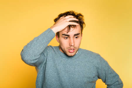 sad worried distraught scared afraid man pulling hair out. portrait of a young handsome brunet guy on yellow background. emotion facial expression. feelings and people reaction concept.の写真素材