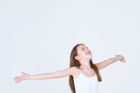 emotion face. happy child looking up her arms out sideways as if in the rain. little girl portrait on white background. mood feelings personality and facial expression conceptの写真素材