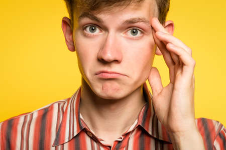 Puzzled confused bewildered pensive man thinking of something . portrait of a young guy on yellow background. emotion facial expression and feelings concept.の写真素材