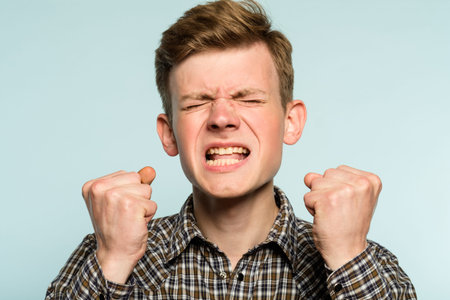 Anger rage and hatred. enraged infuriated man baring his teeth. portrait of a young guy on light...