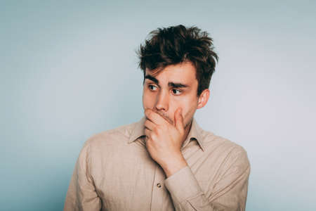 devastated stricken man in despair. failure and loss concept. portrait of a young brunet guy on light background. emotion facial expression. feelings and people reaction.の写真素材