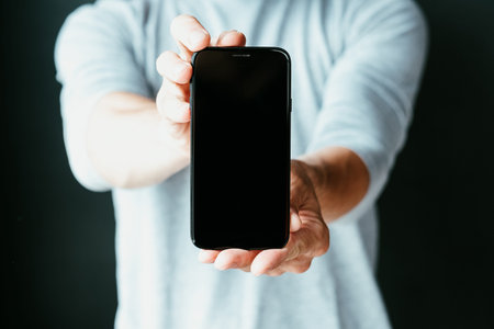 mobile business and e-commerce. online digital marketing. make money on the internet. man holding smart phone with empty black screen.の写真素材