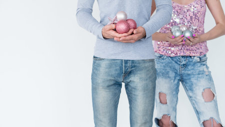 family christmas home decoration traditions. man and woman holding handful of rose gold and silver glittery balls and toys. holiday festive ornament concept.の写真素材