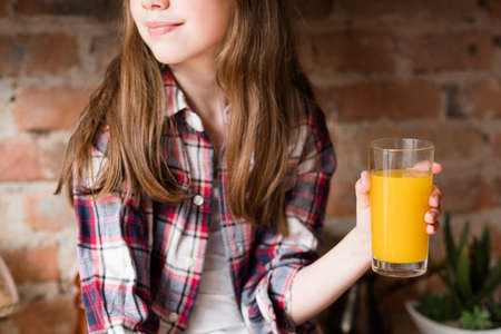 child health and development. useful and tasty drink. vitamin orange juice for balanced nutrition. little girl holding fresh fruit beverage in a glassの写真素材