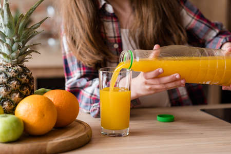 vegetarian or balanced vegan diet for kids. natural delicious organic orange juice. little girl pouring fresh fruit beverage from a bottleの写真素材